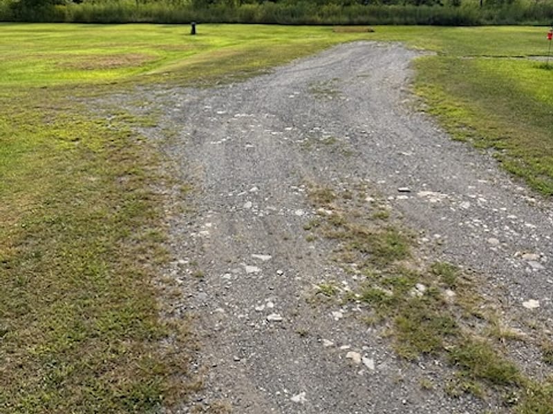A washed-out gravel two-track driveway before regrading