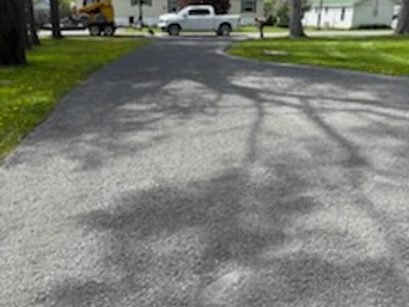 A finished residential driveway with a truck and equipment at the far end