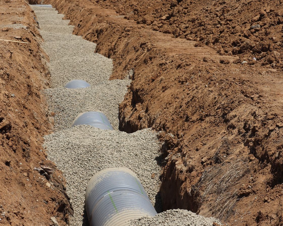 A drain line bedded in crushed stone in an open trench